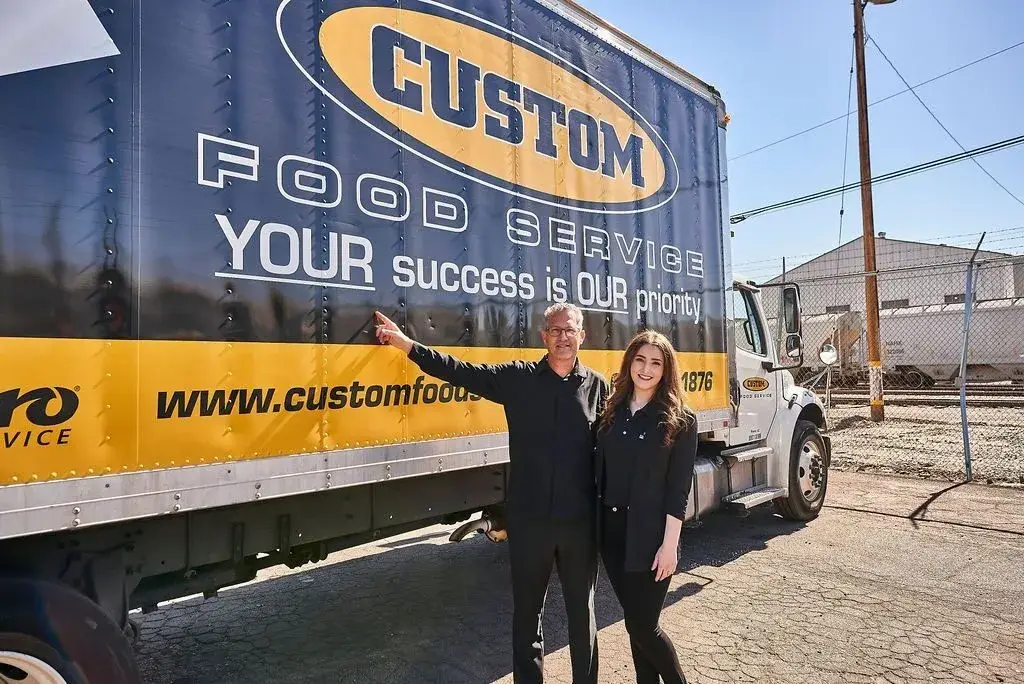 Custom Food Service representatives standing beside a CFS delivery truck