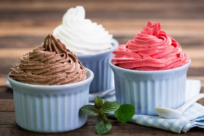 Three ceramic cups filled with chocolate, white, and strawberry whipped cream toppings, ideal for wholesale food suppliers and dessert manufacturers.