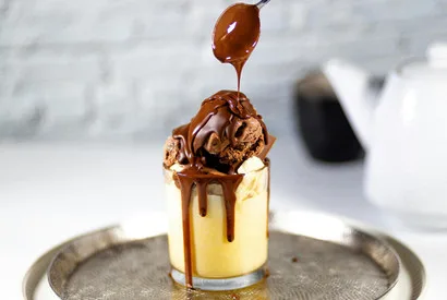 Professional chocolate caramel drip pouring over layered dessert, showcasing premium plating techniques for foodservice and wholesale pastry suppliers.