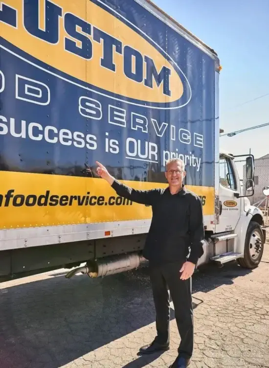 Man beside Custom Food Service truck, showcasing commitment to customer satisfaction and quality.