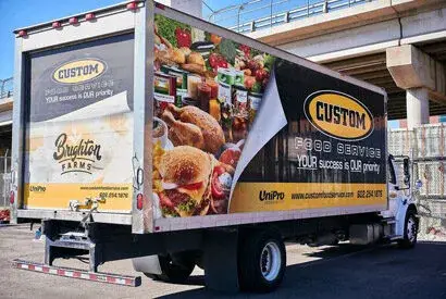 Custom food service truck showcasing Brighton Farms and UniPro, parked in an industrial area.