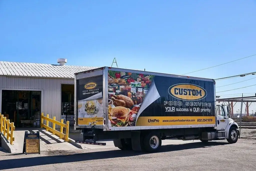 Custom Food Service delivery truck at warehouse, showcasing food supply and logistics efficiency.