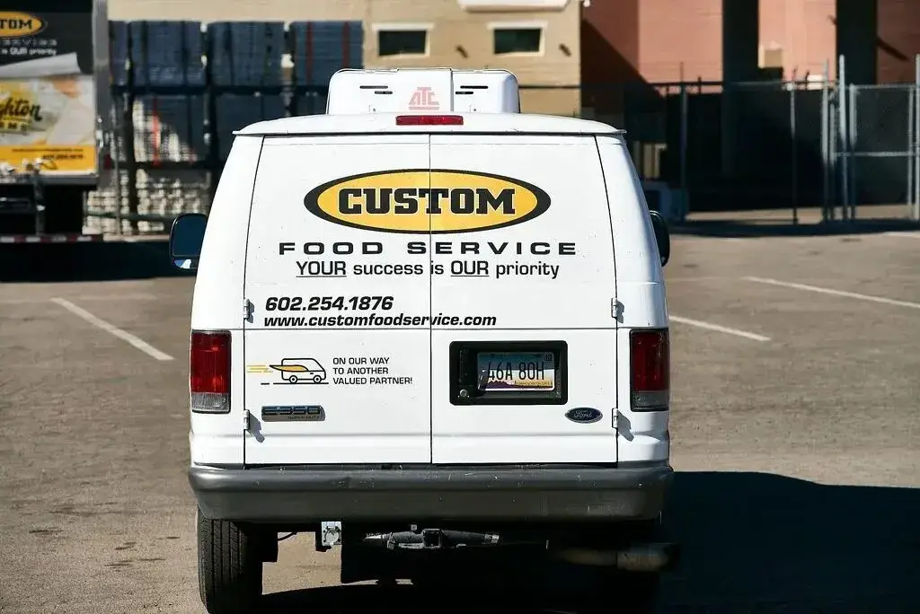 Branded delivery van for Custom Food Service parked in an industrial area, showcasing professionalism.