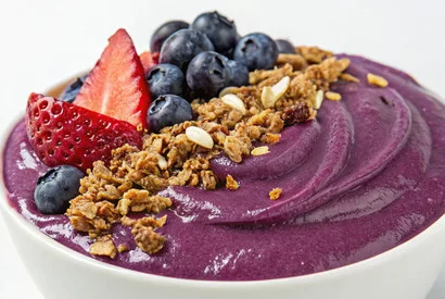 Professional acai bowl featuring vibrant purple puree topped with fresh strawberries, blueberries, and crunchy granola for food service suppliers.