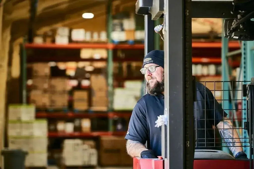Forklift operator in a busy warehouse, managing inventory with precision and safety.