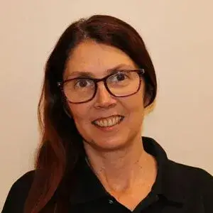 Warm, approachable woman in round glasses, smiling confidently in a professional portrait.