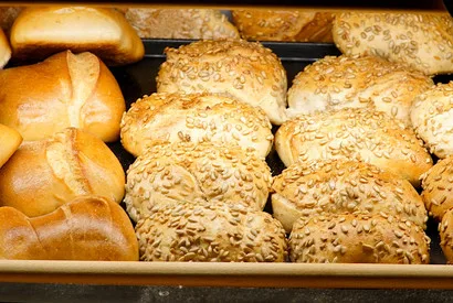 Wholesale bakery display featuring assorted bread rolls including seeded buns and plain rolls, ideal for food distributors and commercial foodservice suppliers.